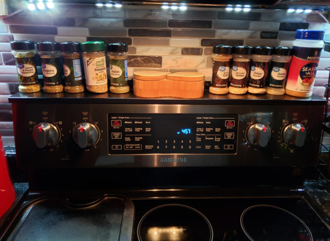 A reviewer's stove with a lineup of various spices on the magnetic shelf