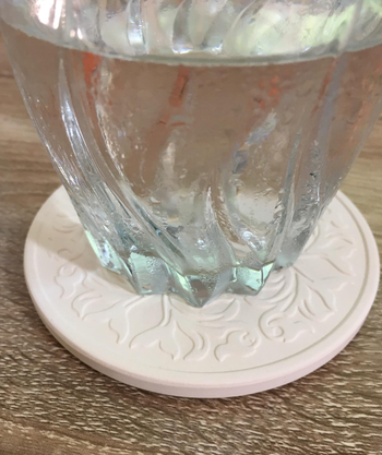 A glass filled with water, resting on an intricately designed coaster