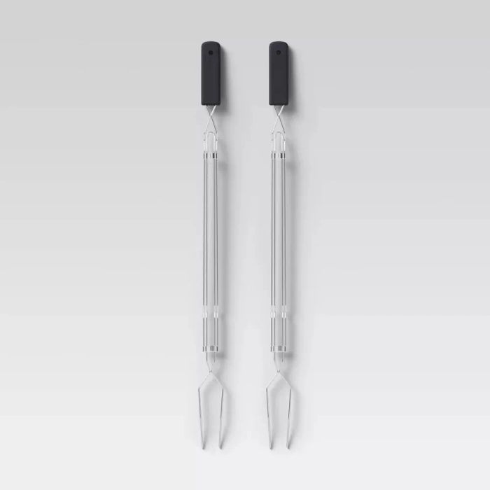 Two barbecue forks with sleek black handles are placed side by side against a simple background.