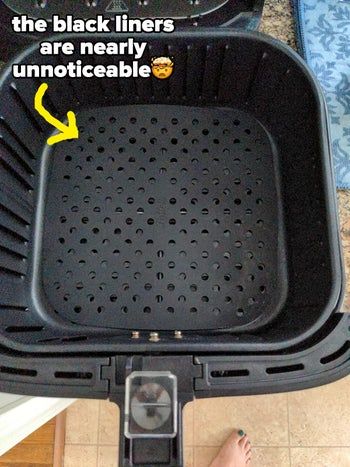 A reviewer demonstrates the black liners placed inside the air fryer.