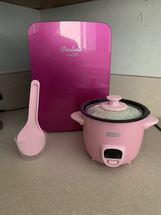 A reviewer's photo showing the pink mini rice cooker on the counter in front of a mini fridge.