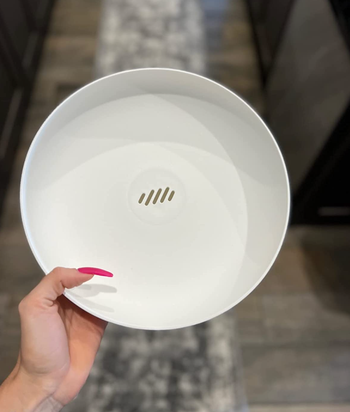 A reviewer demonstrates the subtle slits in the fruit bowl that allow water to drain out