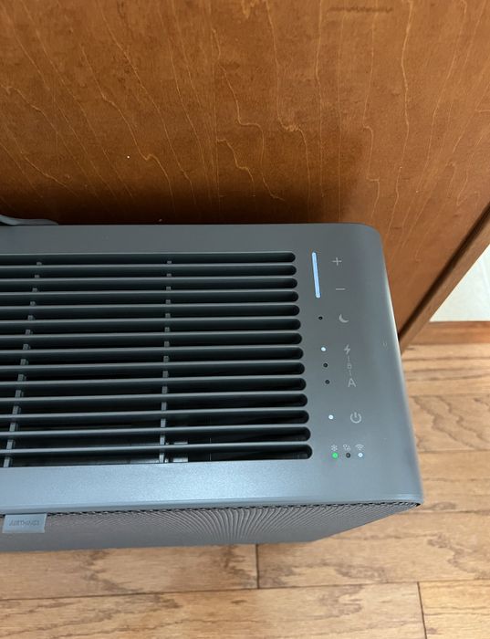 Top view of a sleek, modern air purifier with various control buttons for power, fan speed, timer, and more.