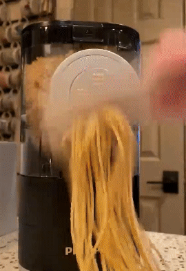 A GIF showing a reviewer slicing pasta as it is extruded from the pasta maker