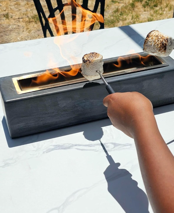 A person roasting marshmallows over a tabletop fire pit