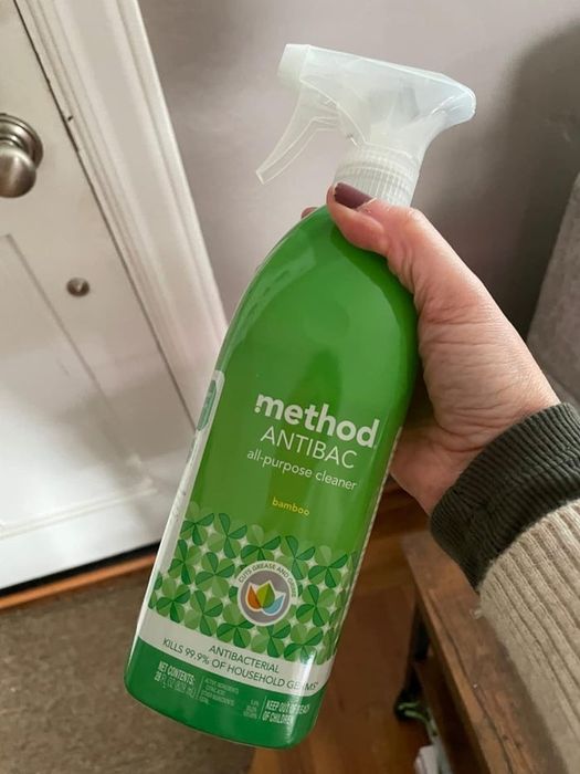 A hand grips a bottle of Method Antibac all-purpose cleaner labeled ‘bamboo,’ formulated to eliminate 99.9% of household germs.