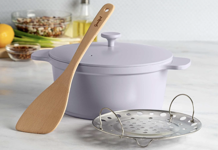 purple Dutch oven accompanied by a steaming basket and a wooden spoon