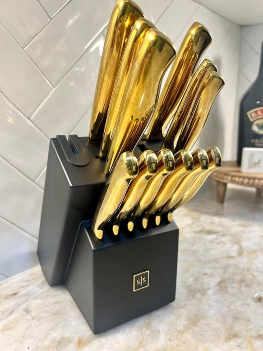 A black knife block displays a full set of gleaming gold kitchen knives, organized neatly on a kitchen counter