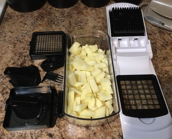 A reviewer’s photo showcasing the chopper, its attachable blades, and a bin filled with freshly chopped potatoes