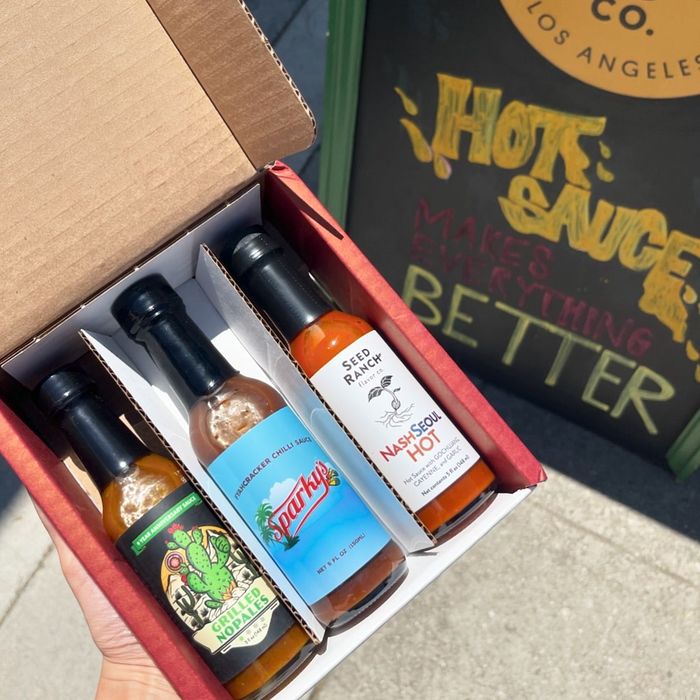 An open box containing three different hot sauce bottles: Angry Goat Pepper Co. Hippy Dippy Green, Sparky's, and Seed Ranch Flavor Co.