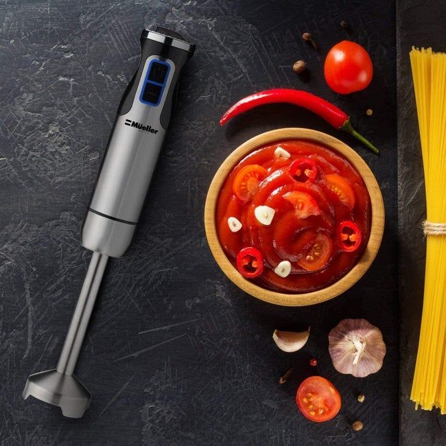 A handheld blender resting next to a container of tomato paste.