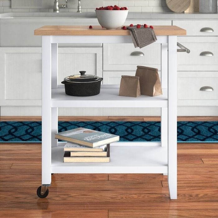 A rolling kitchen cart with two open shelves filled with cookbooks and cookware