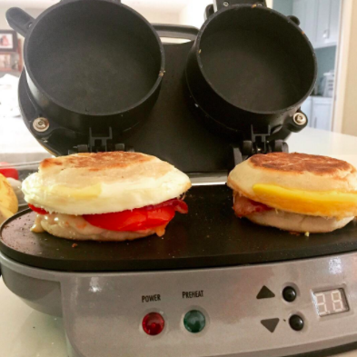 A reviewer prepares egg, ham, and cheese sandwiches using a double breakfast sandwich maker
