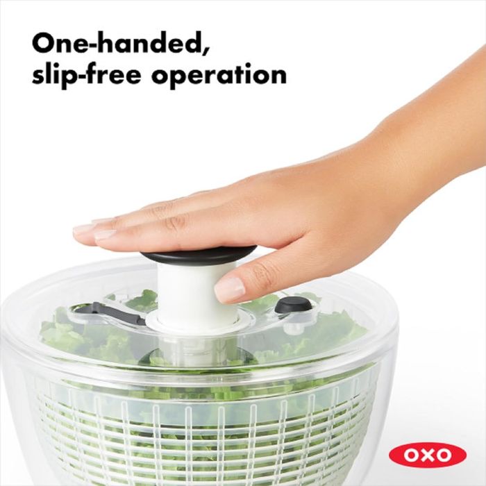 A hand demonstrating the OXO salad spinner with text reading