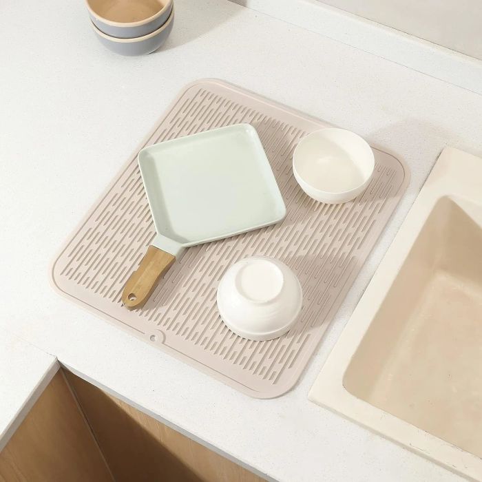 A kitchen counter with a drying mat holding a pan and two bowls, placed next to the sink, as seen in a shopping guide.