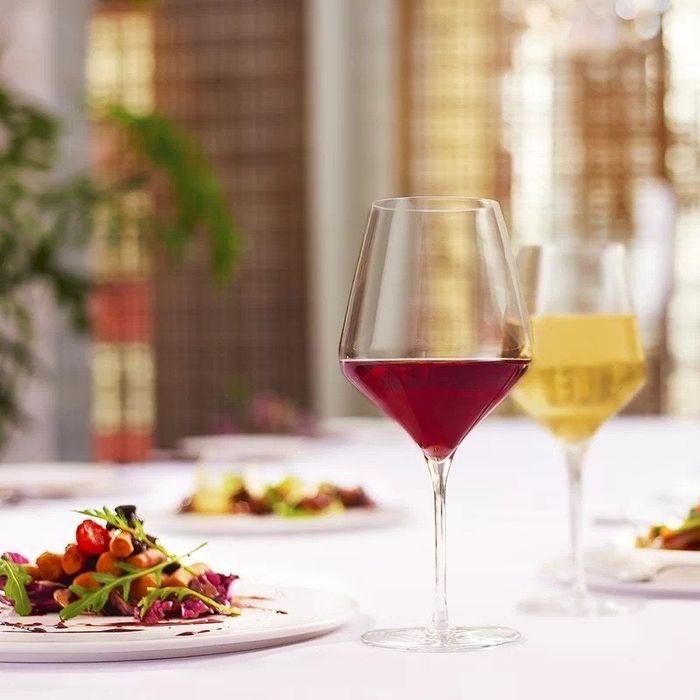 Wine glasses filled with red and white wine, placed beside plates of delicious food.
