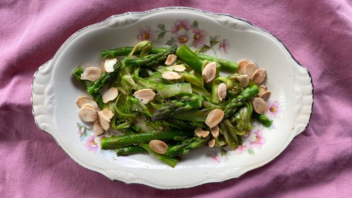Sautéed asparagus served on a plate with sliced almonds.