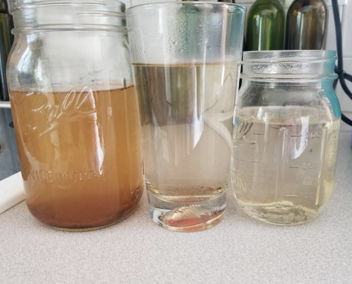 Three cups of dirty water gradually becoming cleaner after each rinse cycle.