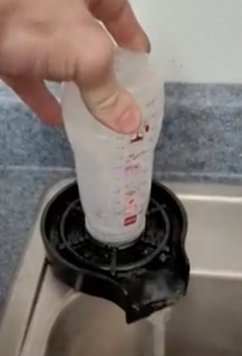 Reviewer cleaning a baby bottle with the rinser.