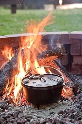 A Dutch oven resting on top of glowing coals in the heart of a blazing fire