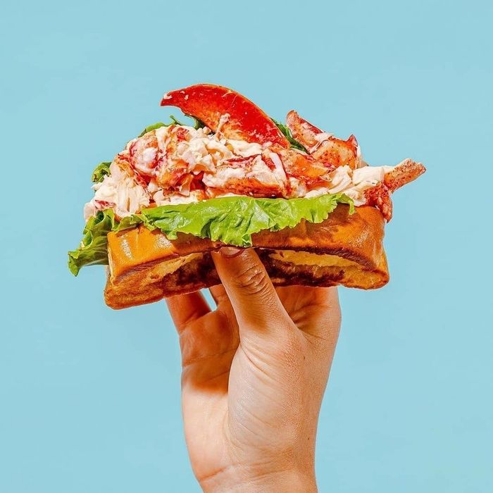 A hand holding a delicious sandwich.