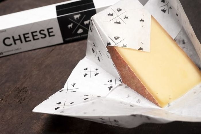 A wedge of hard cheese wrapped in cheese storage paper.