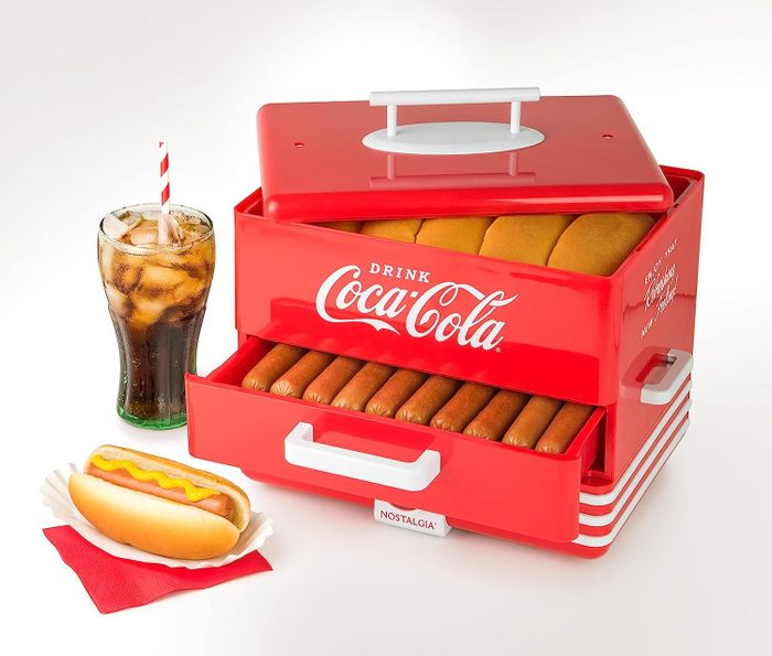 A two-tier hot dog steamer with buns on top and hot dogs below, branded with the Coca-Cola logo.