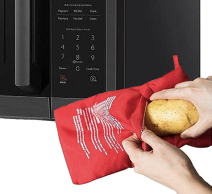 A person microwaving a potato inside a red fabric pouch