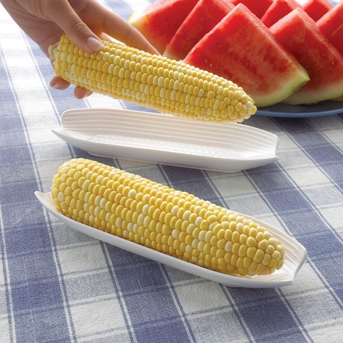 Two ears of corn placed on dishes shaped like corn cobs.