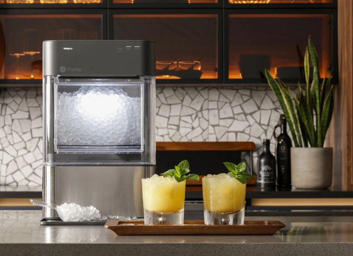 The ice maker featuring a transparent bin and a sleek stainless steel finish