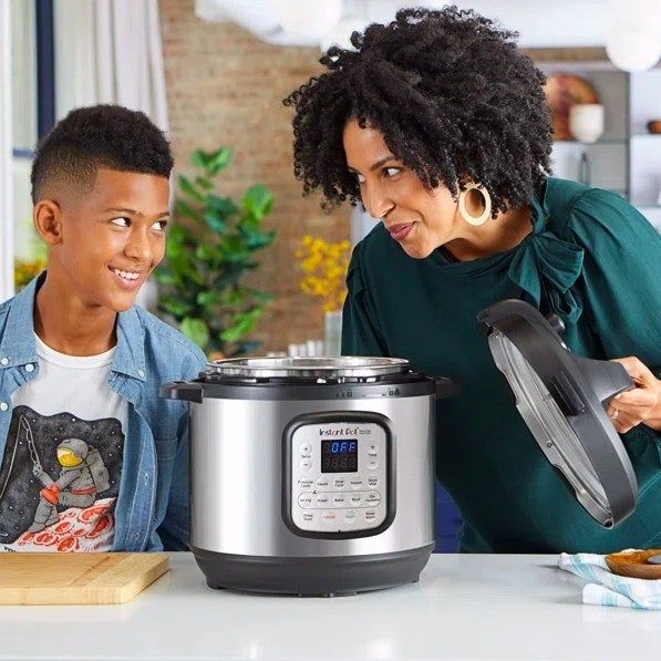 Two individuals standing next to an Instant Pot.