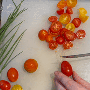 A gif showing my hands slicing a cherry tomato into small, delicate pieces.