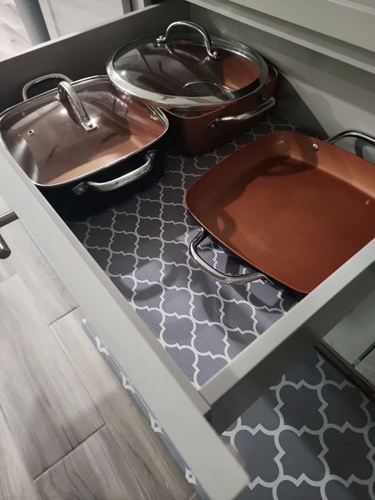 A neatly organized kitchen drawer with pots, pans, and their lids in place.