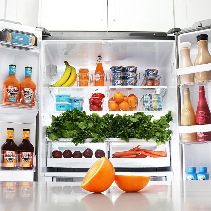 Clear fridge organizer bins filled with produce neatly placed on fridge shelves