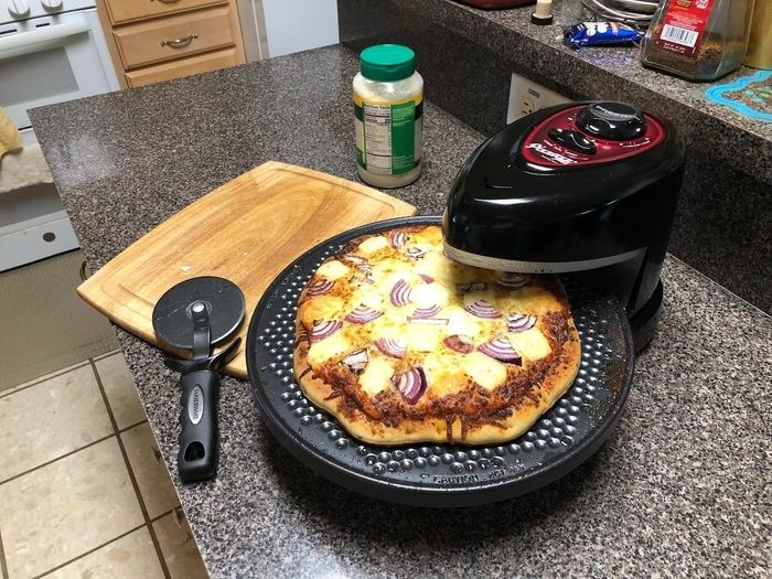 A homemade pizza with various toppings cooking in the rotating oven