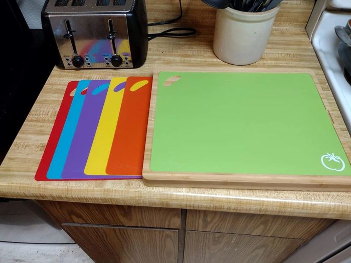 A collection of multicolored cutting boards arranged on a kitchen counter next to a green cutting mat with an apple logo