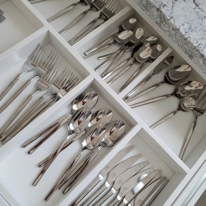 A neatly arranged drawer containing various silverware sets, each perfectly organized in separate compartments, ideal for your shopping list.