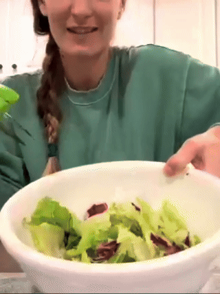 A reviewer using salad scissors to prepare a salad.