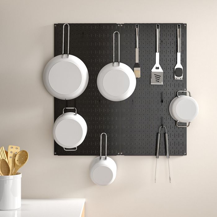 black pegboard displaying pots and pans hanging neatly