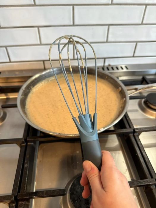 A reviewer showing the whisk in its unfolded, non-collapsed position