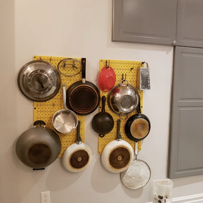 photo of a yellow pan rack on the wall holding several pans