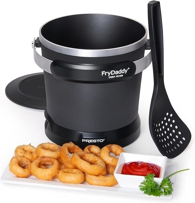 A Presto FryDaddy deep fryer surrounded by fried food, condiments, and a slotted spoon