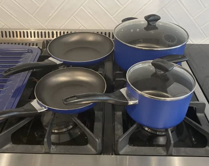 The cookware set displayed on a stove in a sleek dark blue color, perfect for any kitchen setup.
