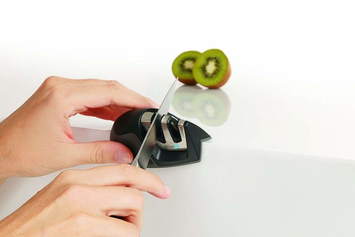 Hands guiding a knife through one of the sharpening channels.