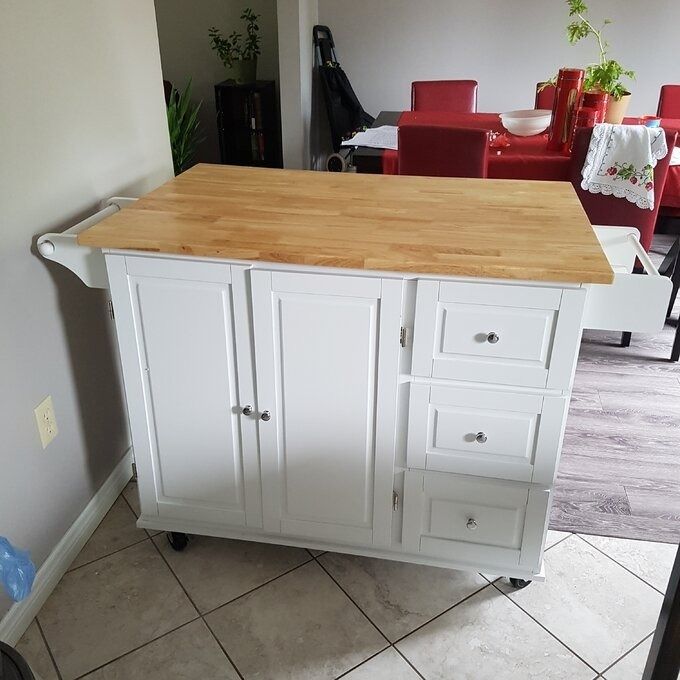 A portable kitchen island featuring a wooden top, cabinet doors, and drawers, offering additional storage and prep space in your home. A perfect solution for organizing your kitchen.