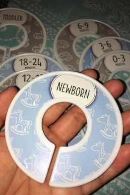 Reviewer holding up a donut-shaped organizer labeled 'newborn' with several other dividers for different months in the background