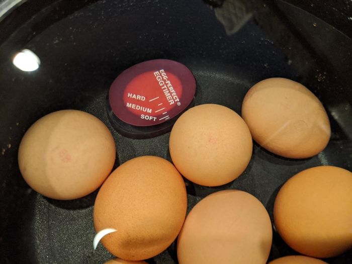 The egg timer placed in a pot of boiling eggs