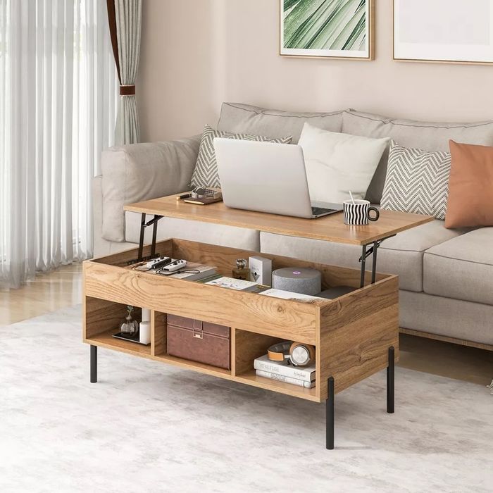 A contemporary living room featuring a lift-top coffee table, revealing extra storage space underneath, with books, decor, and a laptop on top.