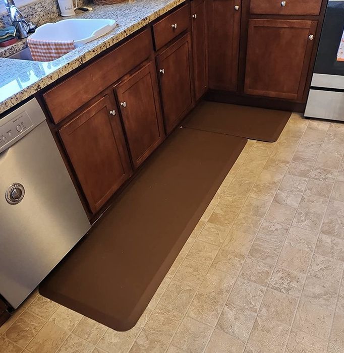 Reviewer photo showing the comfortable brown cushioned mats placed on their kitchen floor.