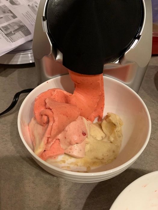 Reviewer's photo of frozen fruit soft serve being dispensed into a bowl alongside other flavors